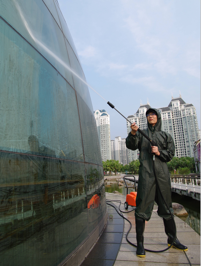 保潔工人正在用高壓清洗機清洗玻離幕墻